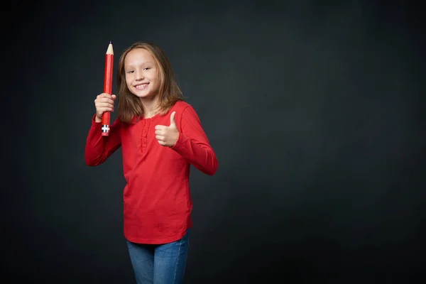 Härlig tjej med stor penna gestikulerande tummen upp — Stockfoto