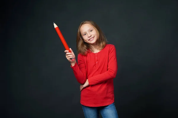 Skolåldern flicka håller stora penna. Tillbaka till skolan-konceptet. — Stockfoto