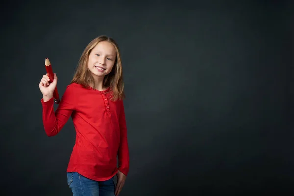 Girl holding big pencil and drawing or writing on blank copy space for text — Stock Photo, Image