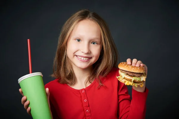 Primer plano de niña sonriente sosteniendo hamburguesa y taza de papel —  Fotos de Stock
