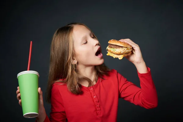 Polárszűrő az éhes kis lány fog harapni egy hamburger — Stock Fotó