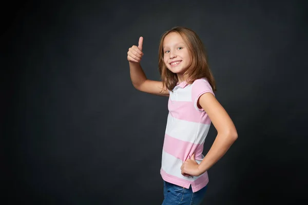 Felice ragazza in età scolare gesticolare pollice in su — Foto Stock