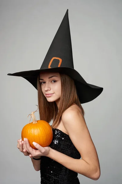 Крупный план игривой ведьмы на Хэллоуин, держащей тыквы — стоковое фото