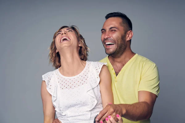 Szczęśliwa para w studio śmiechem nad szary — Zdjęcie stockowe