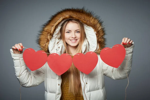 Meisje in winterjas met kap over het houden van vier harten garland — Stockfoto