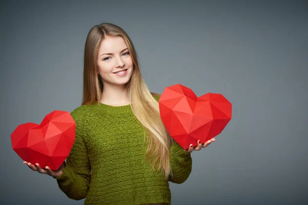 Retrato de una hermosa chica rubia sosteniendo dos formas de corazón — Foto de Stock