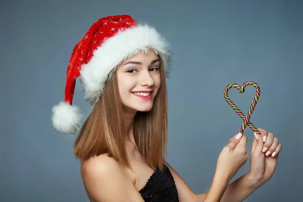 Fille dans Santa chapeau tenant bonbons de Noël en forme de coeur — Photo