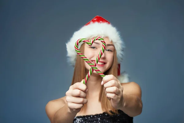 Ragazza a Santa Hat tenendo caramelle di Natale a forma di cuore — Foto Stock