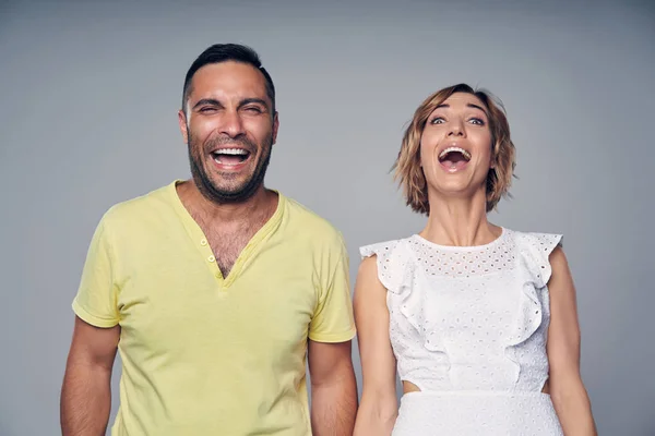 Pareja feliz en el estudio riendo sobre gris —  Fotos de Stock