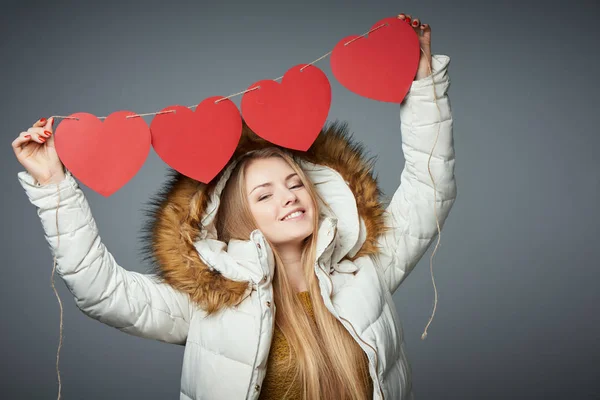 Девушка в зимнем пальто с капюшоном на руках четыре сердца гирлянды — стоковое фото
