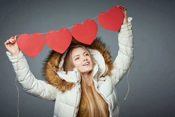 Meisje in winterjas met kap over het houden van vier harten garland — Stockfoto