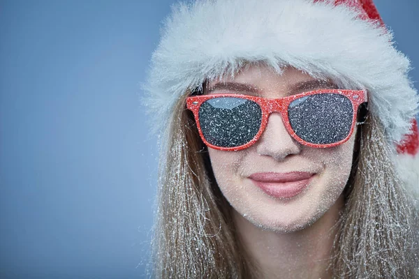 Santa şapka ve güneş gözlüğü takmış yüz karda donmuş kızla — Stok fotoğraf