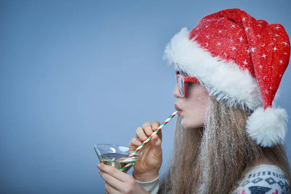 Menina congelada com neve no rosto usando chapéu de Papai Noel e óculos de sol — Fotografia de Stock