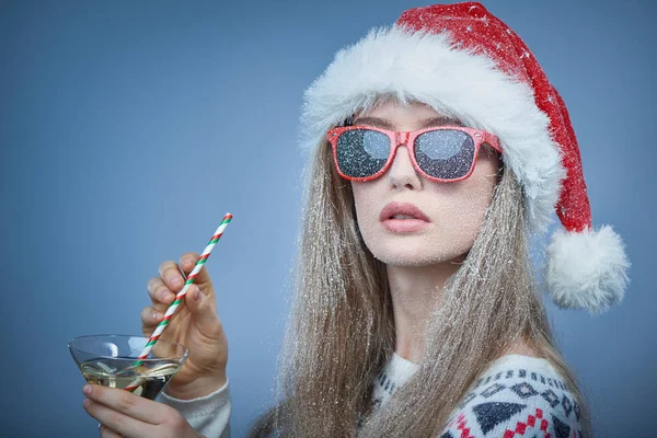 Menina congelada com neve no rosto usando chapéu de Papai Noel e óculos de sol — Fotografia de Stock