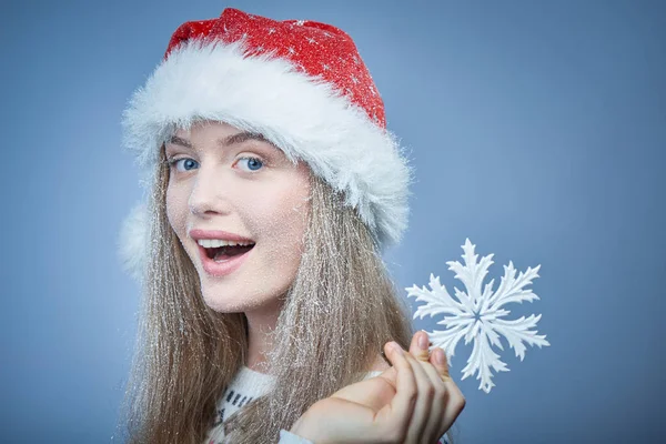 Chica congelada con nieve en la cara con sombrero de Santa celebración de copo de nieve —  Fotos de Stock