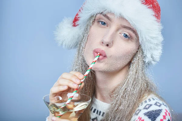 Menina congelada com neve no rosto usando chapéu de Papai Noel beber coquetel — Fotografia de Stock