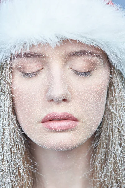Fille congelée avec neige sur le visage portant le chapeau de Père Noël — Photo