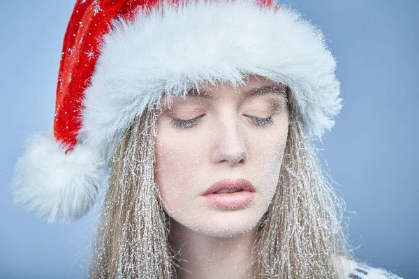 Menina congelada com neve no rosto usando chapéu de Papai Noel — Fotografia de Stock