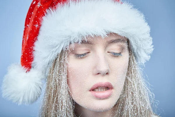 Menina congelada com neve no rosto usando chapéu de Papai Noel — Fotografia de Stock