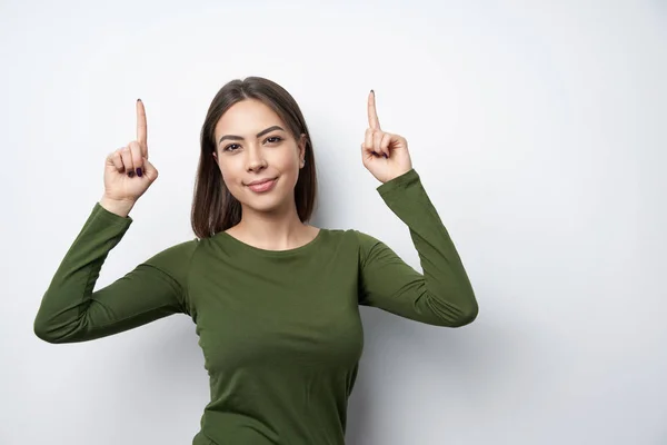 Mujer feliz señalando hacia arriba con dos dedos —  Fotos de Stock