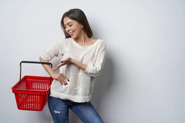 Kvinna som håller visar tom shopping korg pekar — Stockfoto