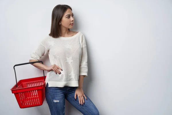Woman holding empty shopping basket looking aside — Stock Photo, Image