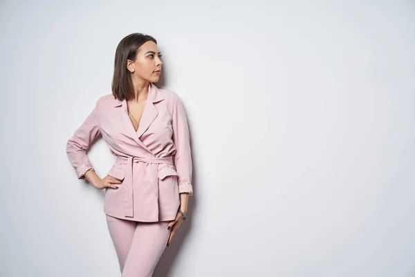 Junge Frau Rosafarbenen Anzug Steht Weißer Wand Und Blickt Seitlich — Stockfoto