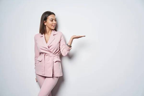 Frau im rosafarbenen Anzug hält Kopierraum auf der Handfläche — Stockfoto