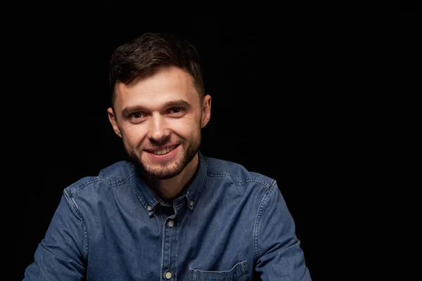 Bonito homem de camisa jeans olhando para a câmera sorrindo — Fotografia de Stock