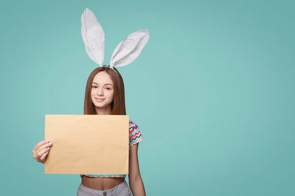 Menina usando orelhas de coelho segurando um envelope carta em branco — Fotografia de Stock