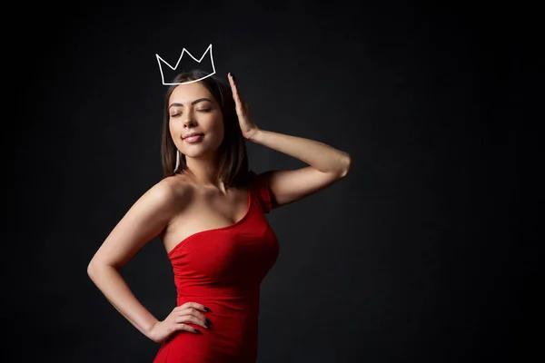 Mulher bonita em vestido vermelho apoiando sua coroa com olhos fechados — Fotografia de Stock