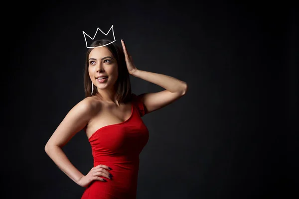 Mulher bonita em vestido vermelho apoiando sua coroa — Fotografia de Stock