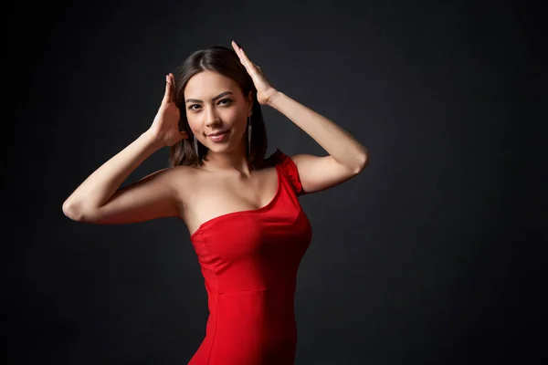 Vacker kvinna i röd klänning stödja något imaginärt på hennes huvud — Stockfoto