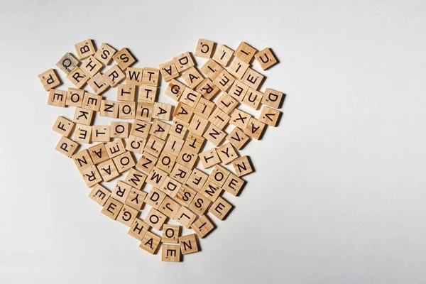 Lettere dell'alfabeto su pezzi quadrati di legno che formano la forma del cuore — Foto Stock