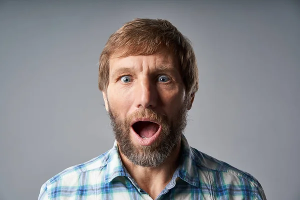 Surprised mature man in checkered shirt with mouth opened — Stock Photo, Image