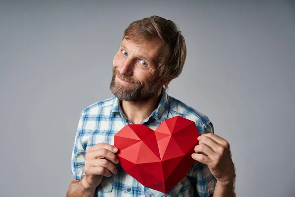 Homme mûr souriant en chemise à carreaux tenant la forme du cœur — Photo
