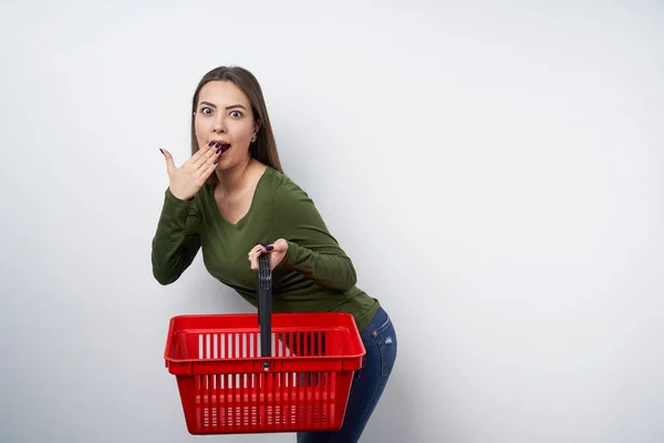 Zaskoczony brunetka kobieta trzymając pusty kosz na zakupy — Zdjęcie stockowe