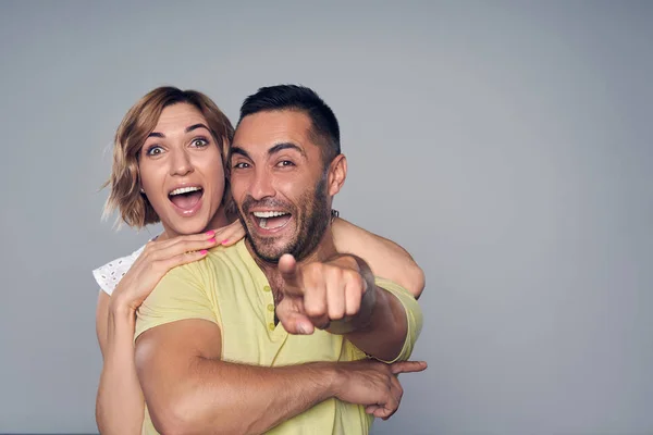 Emocional casal surpreso olhando para a câmera apontando para você — Fotografia de Stock