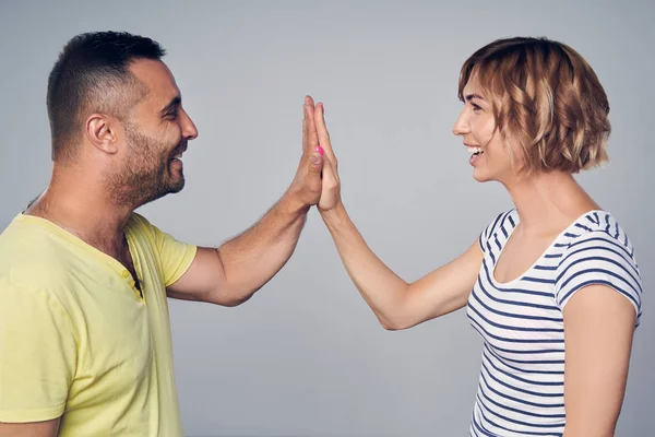 Casal feliz no estúdio rindo sobre cinza — Fotografia de Stock