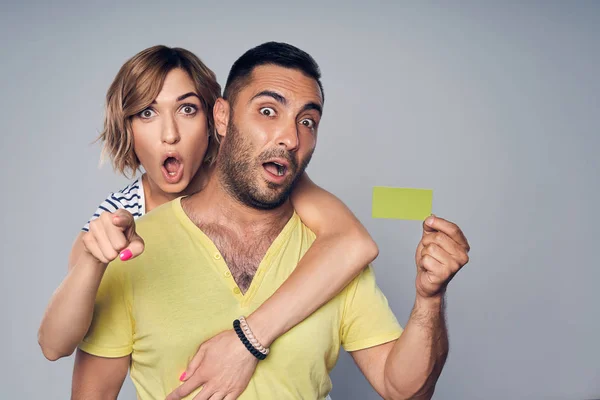 Surpreendido casal surpreso mostrando cartão de crédito em branco e apontando para você — Fotografia de Stock