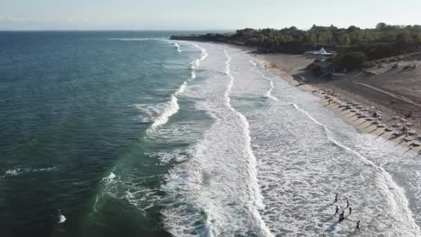 日落时分 人们沿着海滩飞翔 沿着水边行走 海浪在沙滩上破浪而过 鸟瞰无人机 — 图库视频影像