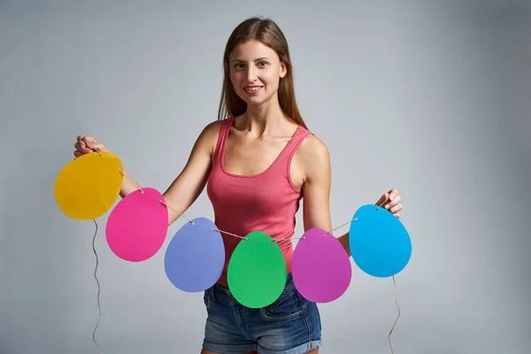 Mujer sonriente sosteniendo guirnalda de huevos de Pascua forma —  Fotos de Stock