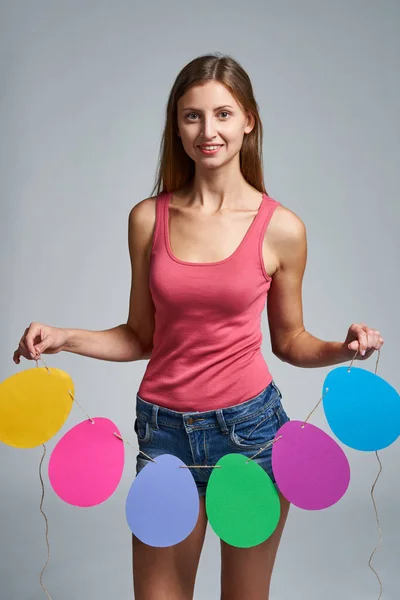 Mujer sonriente sosteniendo guirnalda de huevos de Pascua forma —  Fotos de Stock