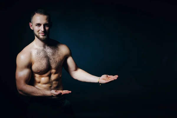 Homem sem camisa muscular segurando um espaço de cópia vazio na palma da mão aberta mostrando no espaço de cópia em branco — Fotografia de Stock