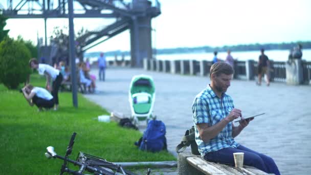 Uomo maturo che naviga su tablet digitale, seduto sulla panchina in un parco — Video Stock