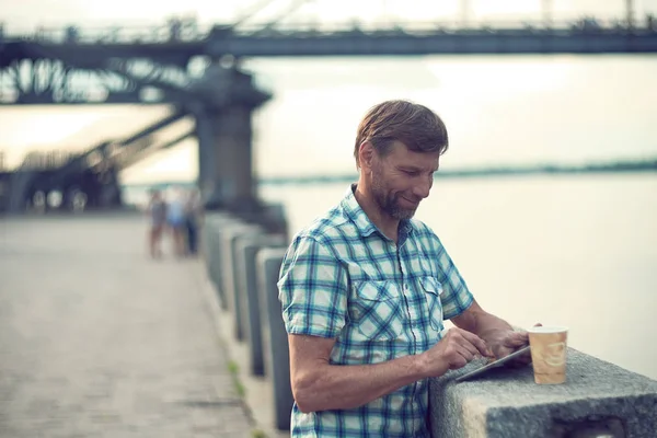 Äldre man surfar på digital Tablet på sommaren, på River Quay — Stockfoto