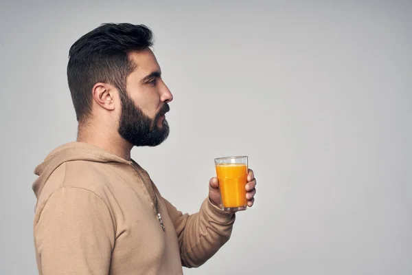 Brodaty mężczyzna trzyma szklankę soku pomarańczowego — Zdjęcie stockowe