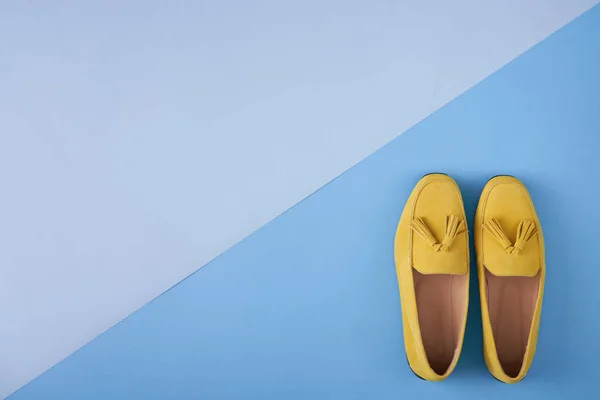 Yellow woman's moccasins shoes over blue background — Stock Photo, Image