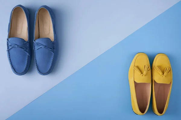 Blue suede man's and yellow woman's moccasins shoes over blue background — Stock Photo, Image