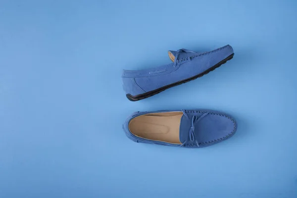 Blue suede man\'s mocassin shoes over blue background